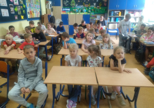 dzieci siedzą w ławkach