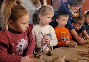 Dzieci tworzą ozdoby choinkowe z gliny.