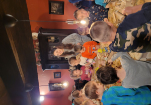 Dzieci skupione przy stole tworzą ozdoby choinkowe z gliny.