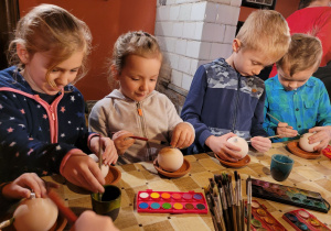 Dzieci malują gliniane bombki.