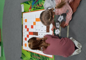 Dziewczynki układają kolorowe kwadraty zgodnie z kodem.
