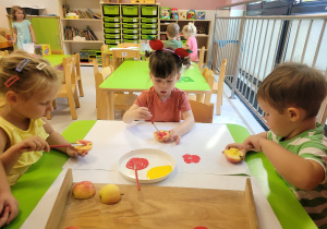 Dzieci wykonują stemple z jabłka.