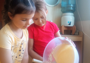 Dziewczynki wylewają ciasto na formę