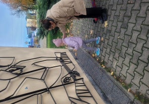 Dziewczynka stawia znicz pod pomnikiem.