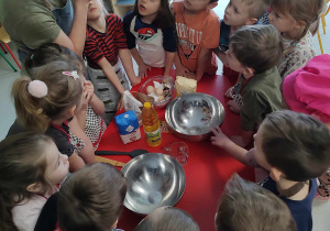 pani Karolina wyjaśnia dzieciom jakie składniki należy dodać do ciasta