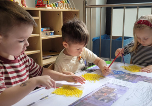 Dzieci malują folię bąbelkową na żołto.