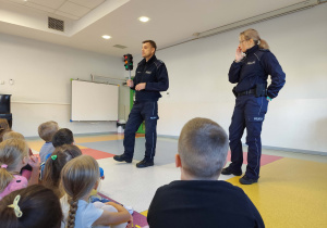 Policjanci demonstrują sygnalizator świetlny i przypominają zasady obwiązujace na przejściu dla pieszych.