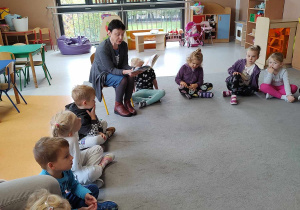 Dzieci siedzą w kole i słuchają pani z biblioteki