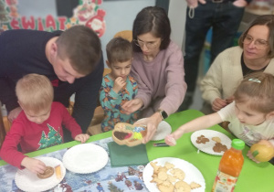 Wspólnie z rodzicami dzieci dekorują pierniki.