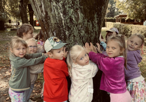 Dzieci przytulają się do drzewa