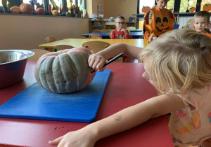 Dziewczynka maluje na dyni śmieszną buzię