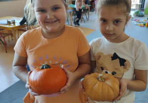 Dziewczynki pozują z przyniesionymi dyniami