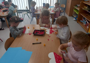 Sarenki wyklejają serce w barwach biało czerwonych.