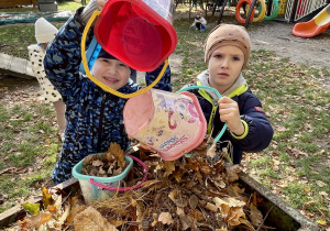 Chłopcy wysypują zebrane liście