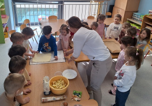 Dzieci z słuchają przepisu jak zrobić jabłkowe na ciasteczka.