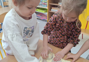 Dziewczynki wykrawają koło na ciasteczko.