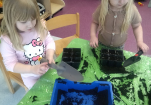 dzieci napełniają doniczki ziemią