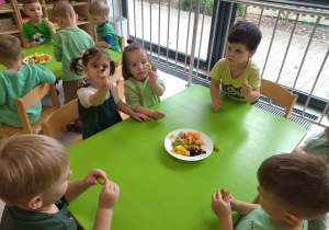 dzieci robią i jedzą koreczki owocowe