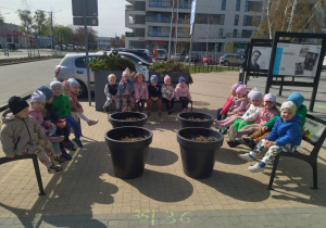 dzieci siedzą na ławeczkach