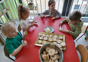 Dzieci smarują masłem wypieczone bułeczki
