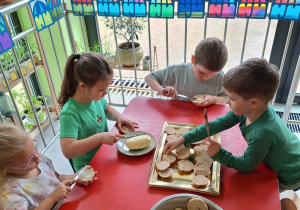 Dzieci smarują bułeczki masłem