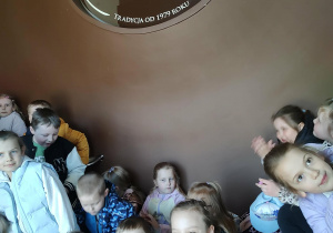 Dzieci pozują do zdjęcia przy logo zakładu cukierniczego