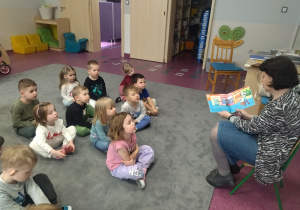 dzieci siedzą na dywanie i słuchają bibliotekarki