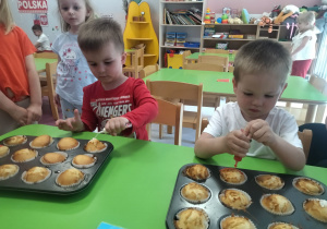 chłopcy ozdabiają babeczki