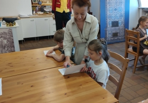 Pani prowadząca stawia kleksa na kartce Alicji