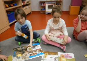dzieci na dywanie oglądają książki