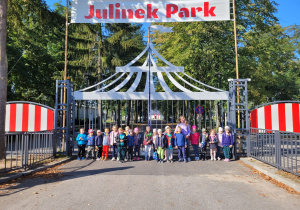 Dzieci pozują do zdjęcia przy bramie głównej parku rozrywki.
