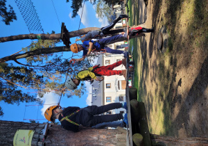 Dzieci pokonują przeszkody parku linowego.