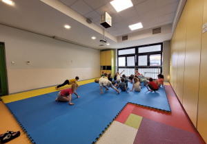 Dzieci wykonują ćwiczenie prezentowane przez trenerkę.
